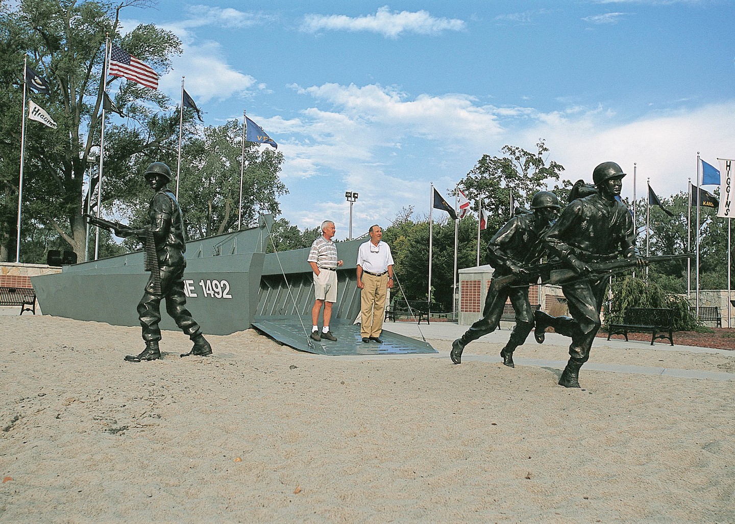 Two visitors standing among the soldier statues and Higgins boat at the Andrew Jackson Higgins Monument.