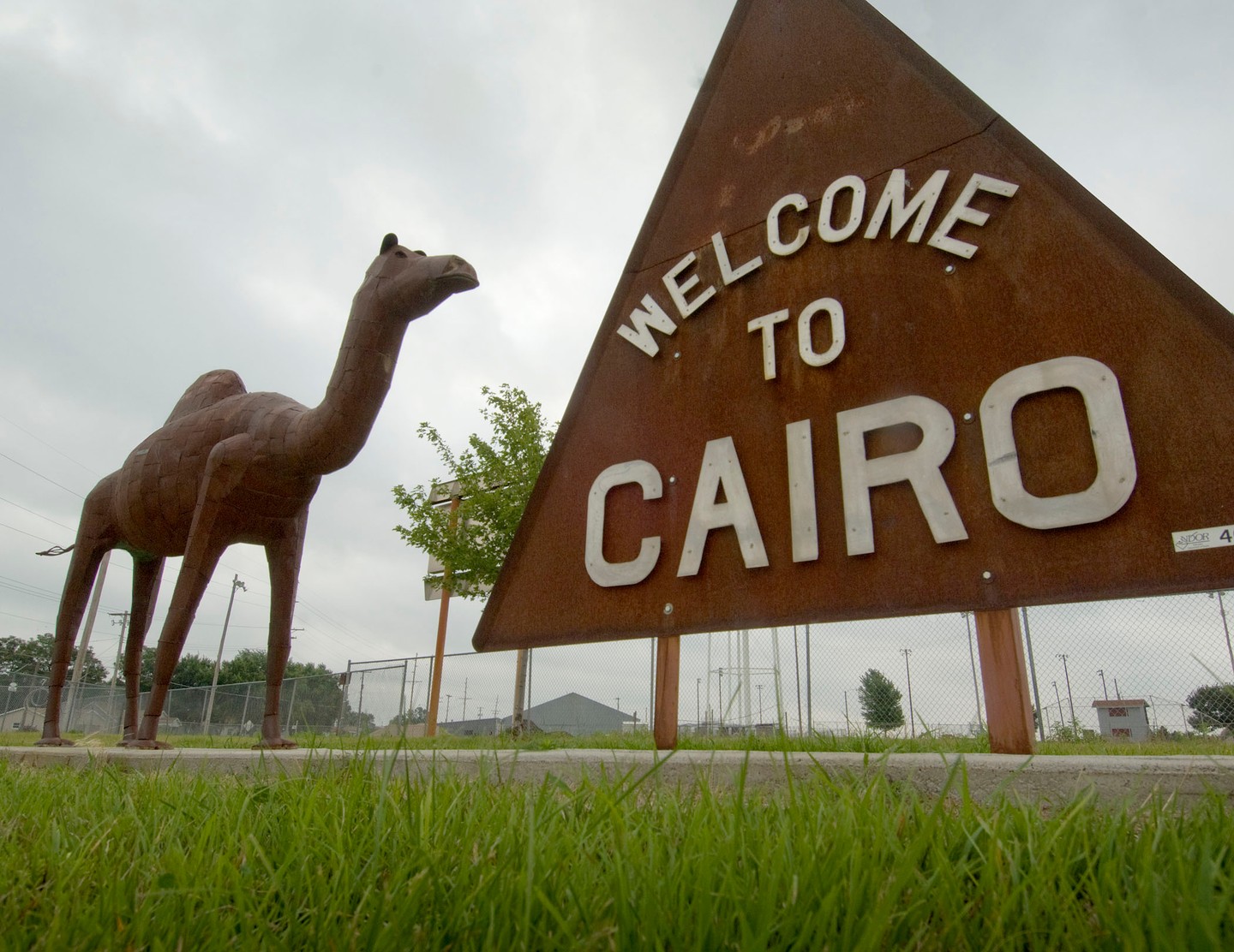 Welcome to Cairo sign with a metal camel statue next to it. 