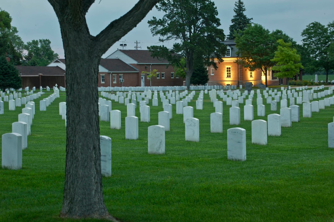 Lines of headstone with buildings in the background at Fort McPherson National Cemetery.