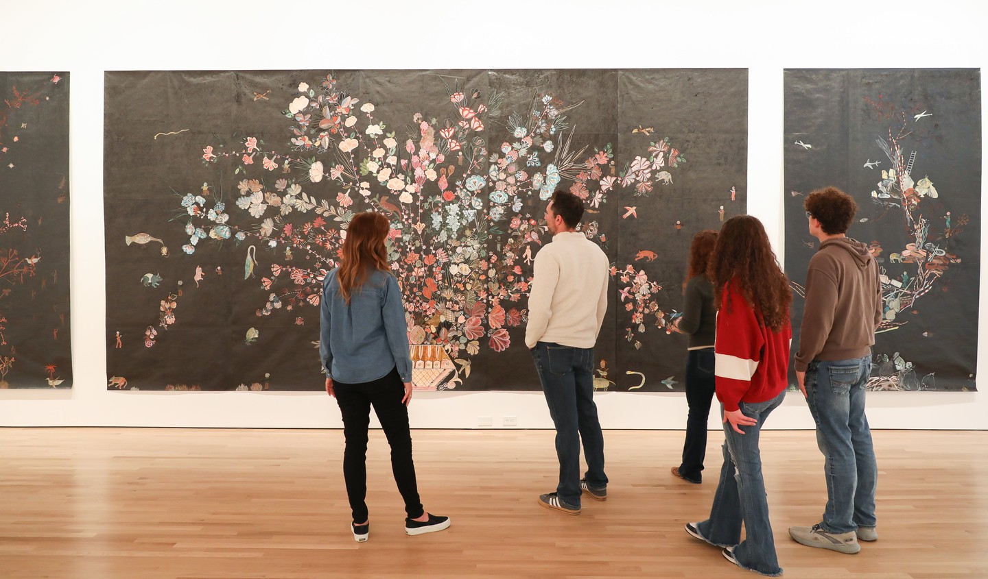 Folks gathered in front of a set of artwork at Museum of Nebraska Art.