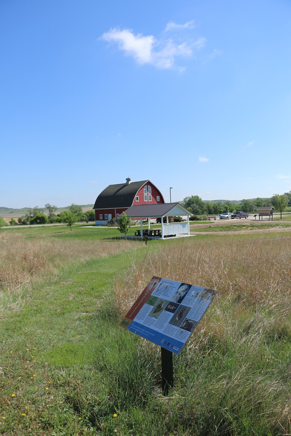 View of Sandhills scenery with a historical display and the red barn that houses the Sandhills Journey Scenic Byway Visitor Center in the background. 