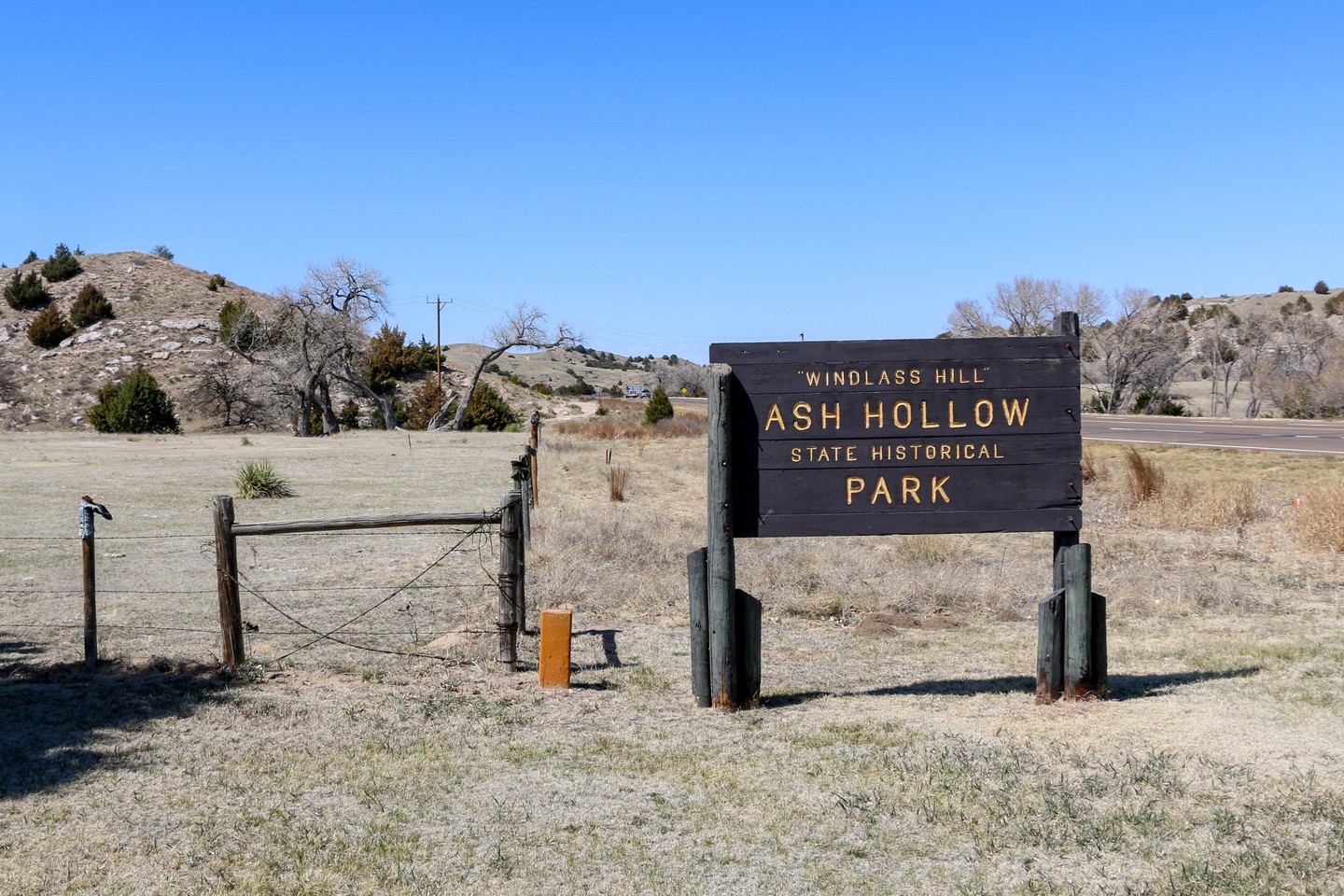 A sign for Ash Hollow State Historical Park, with scenic views in the background.
