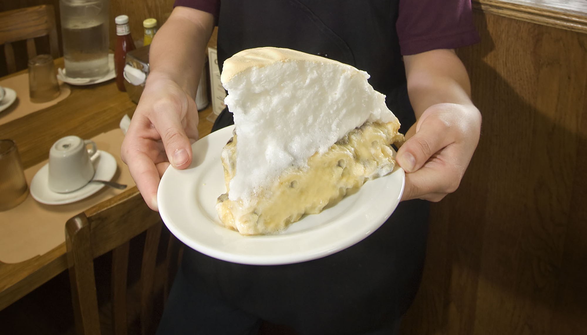 A waitress holding a plate with a massive piece of pie at Crystal Cafe.