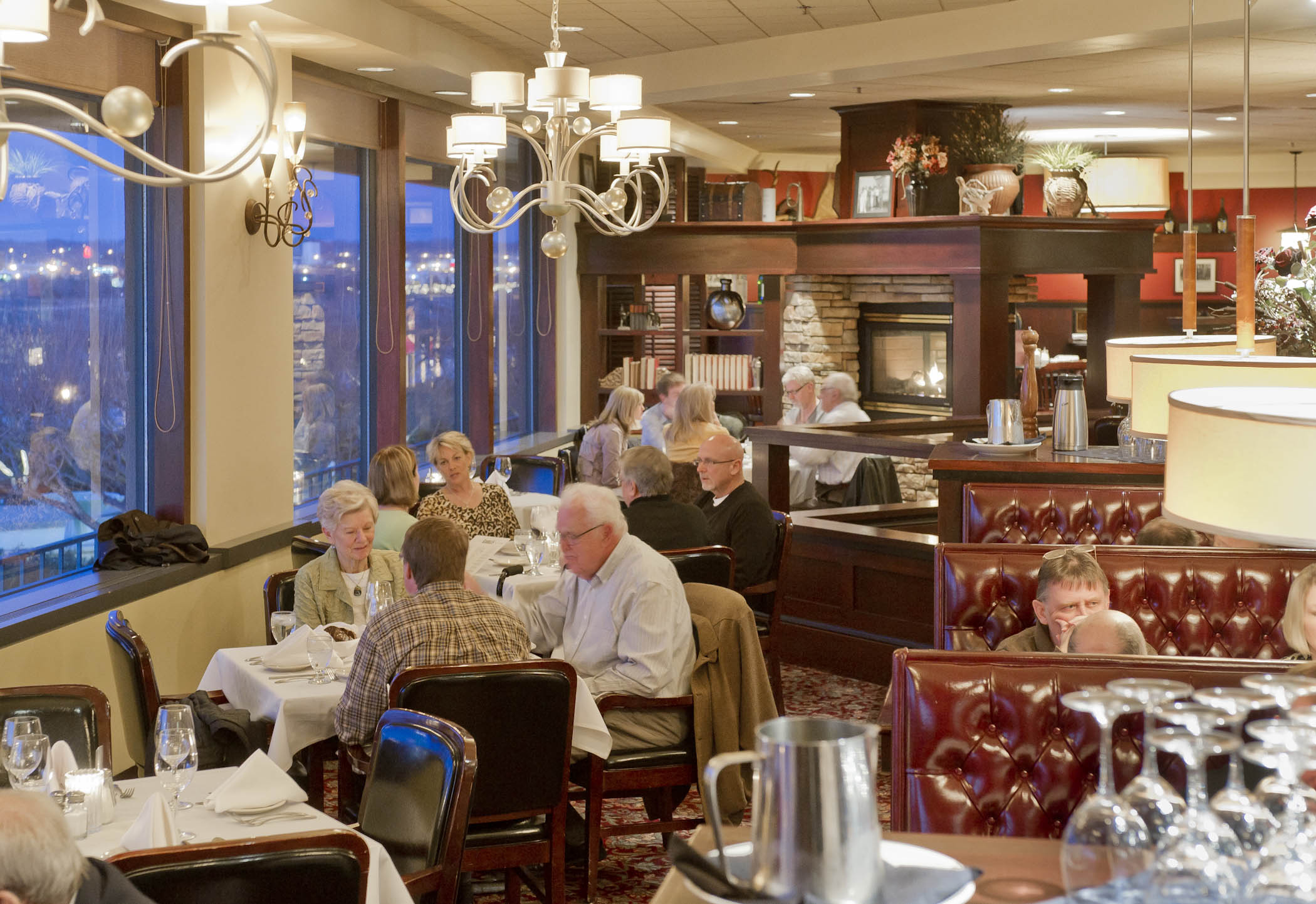Folks eating in the dining room next to large windows overlooking the river inside Kahill's Chophouse.