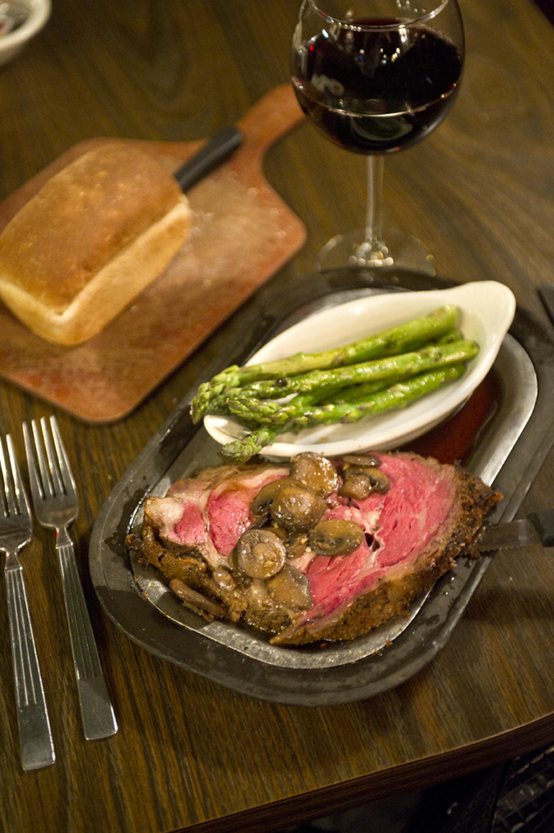 Nebraskan steak with mushrooms on top and a side of asparagus.
