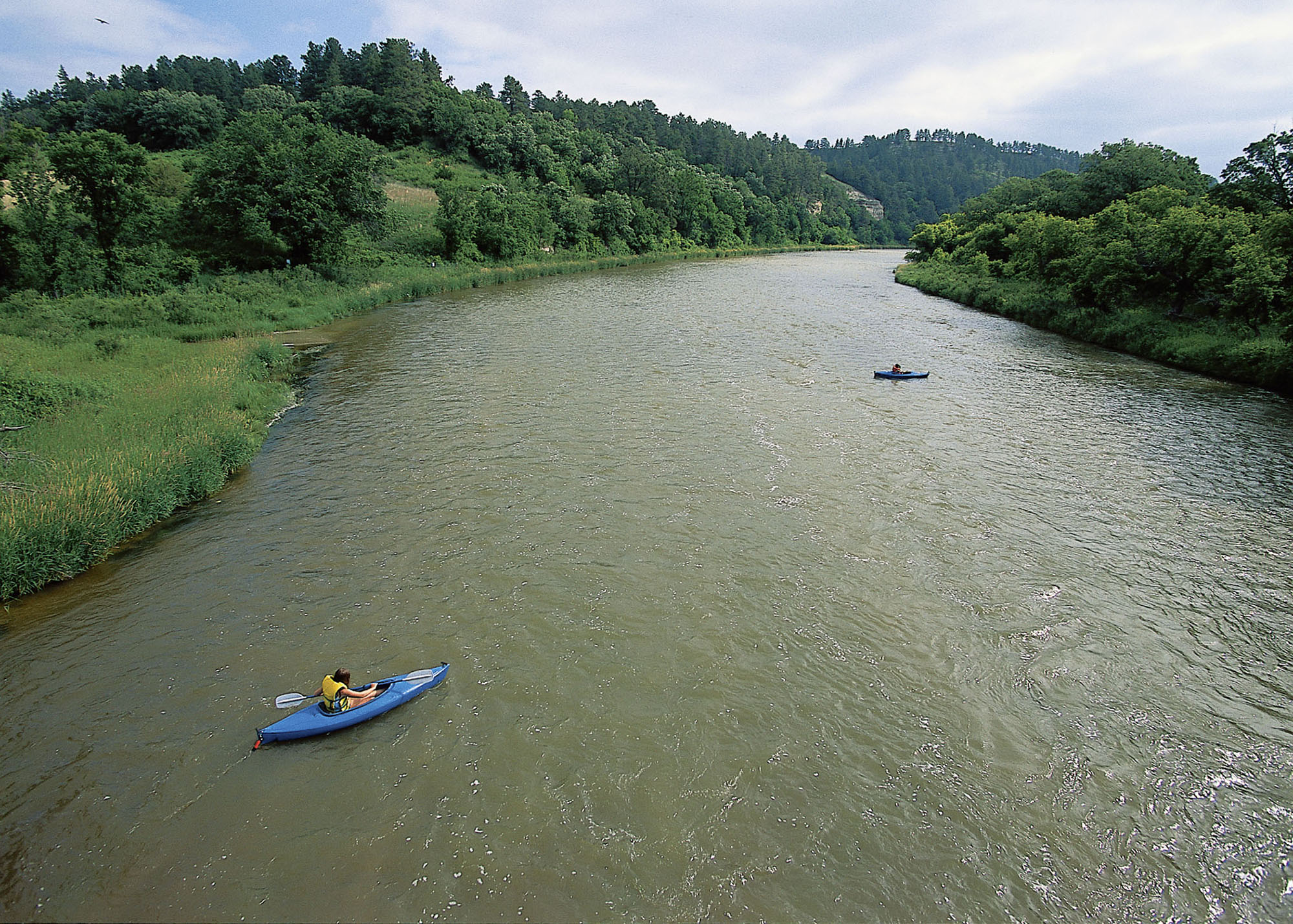 Two kayakers explore the lush banks of the Niobrara National Scenic River in Nebraska.