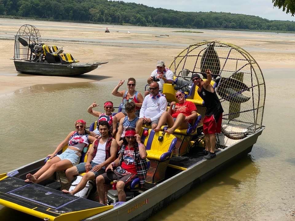 A group of enthusiastic visitors sits and poses for a photo on an airboat with a crew from Woody's Airboat Tours near Fremont, Nebraska.
