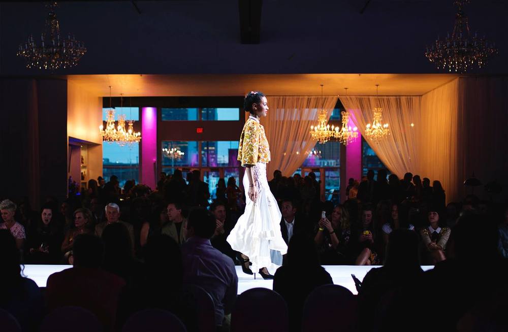 A model walking the runway with a crowd surrounding at Omaha Fashion Week.