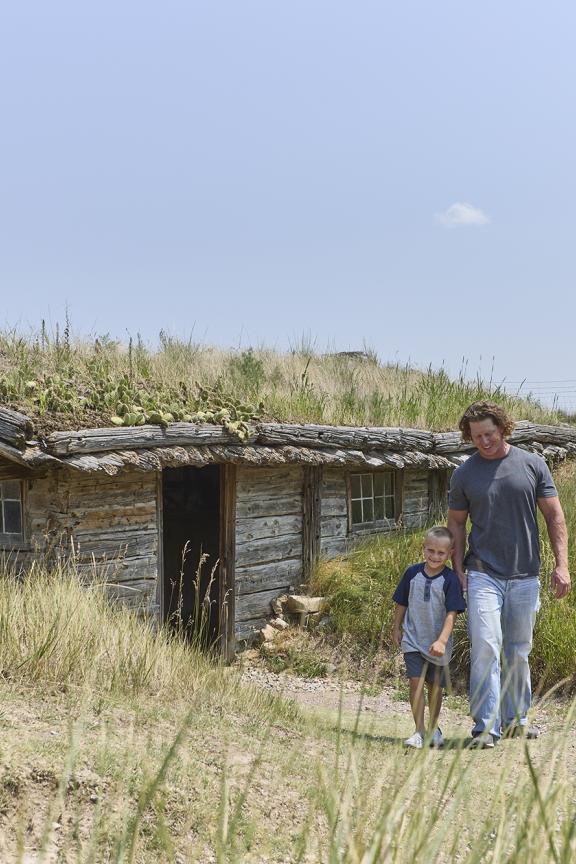 A man and child walking from the historic Bordeaux's Trading Post at Museum of the Fur Trade.