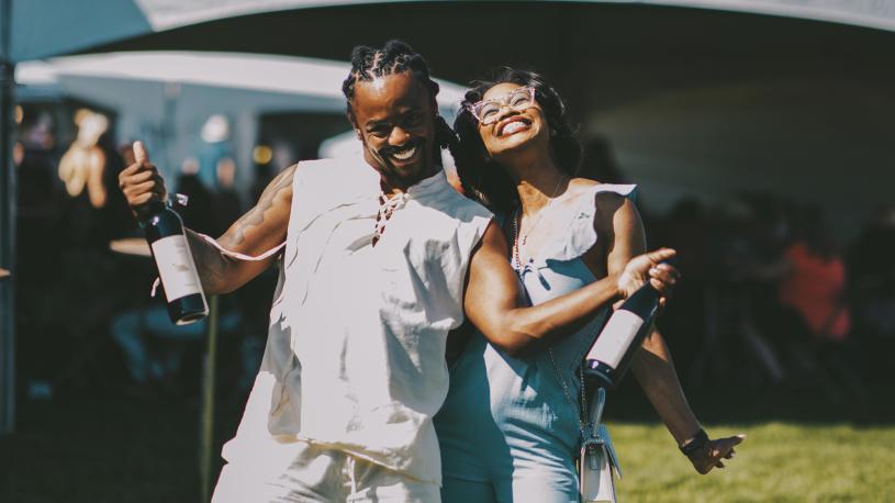 A couple posing for a picture, as the man holds up two bottles of wine, at Toast Nebraska wine festival.