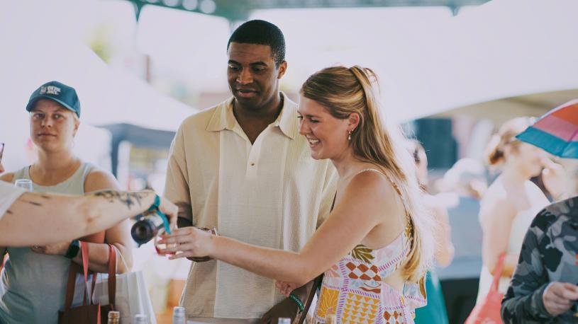 A man and woman getting their tasting glasses filled with wine at Toast Nebraska wine festival.
